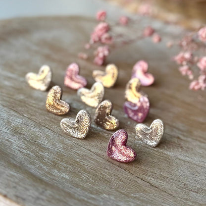 Pienet sydän nappikorvakorut glitterin kimalluksella.