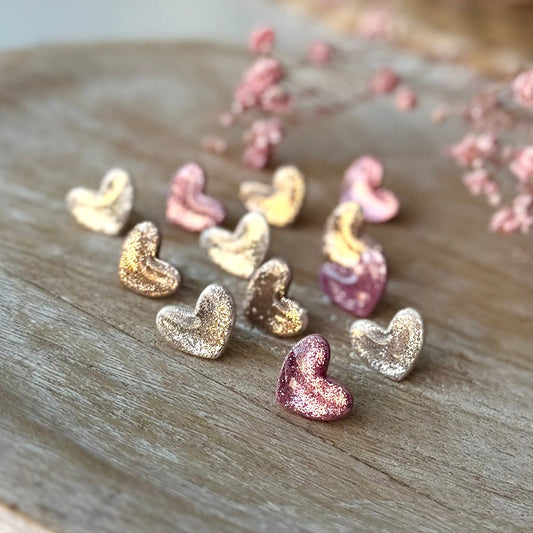 Pienet sydän nappikorvakorut glitterin kimalluksella.